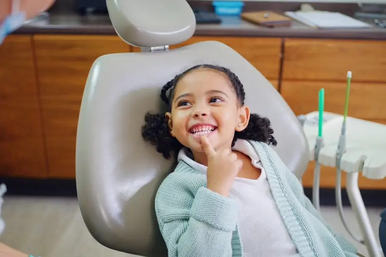 Child smiling in dental chair, showing positive pediatric dental visit experience after Tooth Extractions in Spirit Lake, Iowa