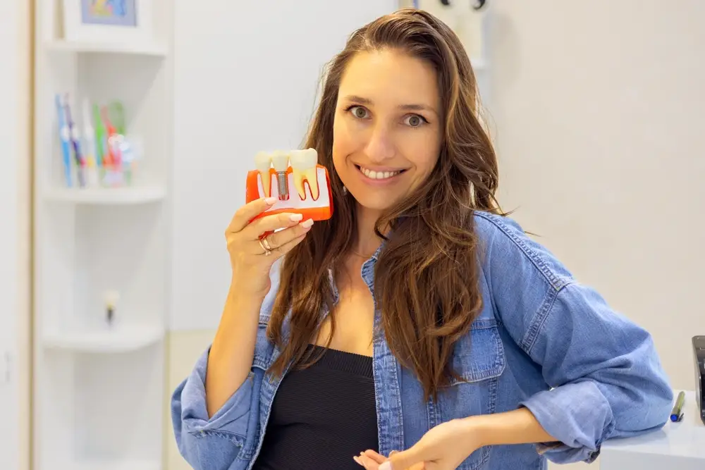 Woman holding dental model, demonstrating Dental Implants and dental education