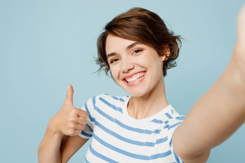 Smiling woman giving thumbs up, representing successful dental treatment results. Your Spirit Lake Dentist: The Beacons of Dental Excellence