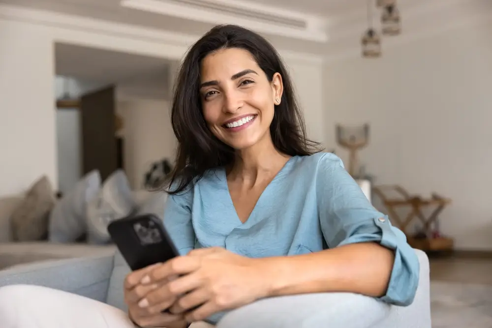Smiling woman using phone, representing easy dental appointment scheduling